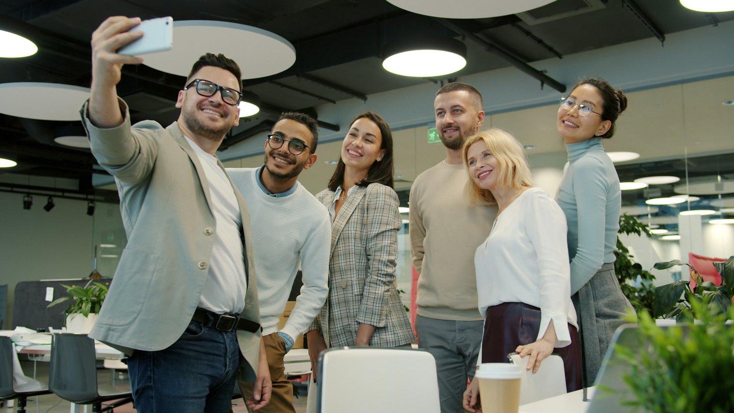 Teammitglieder machen ein Selfie in einem hellen, modernen Büro.